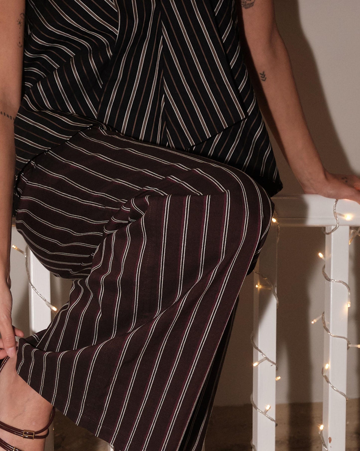 Calças às riscas de pernas largas com pregas, cor castanha.