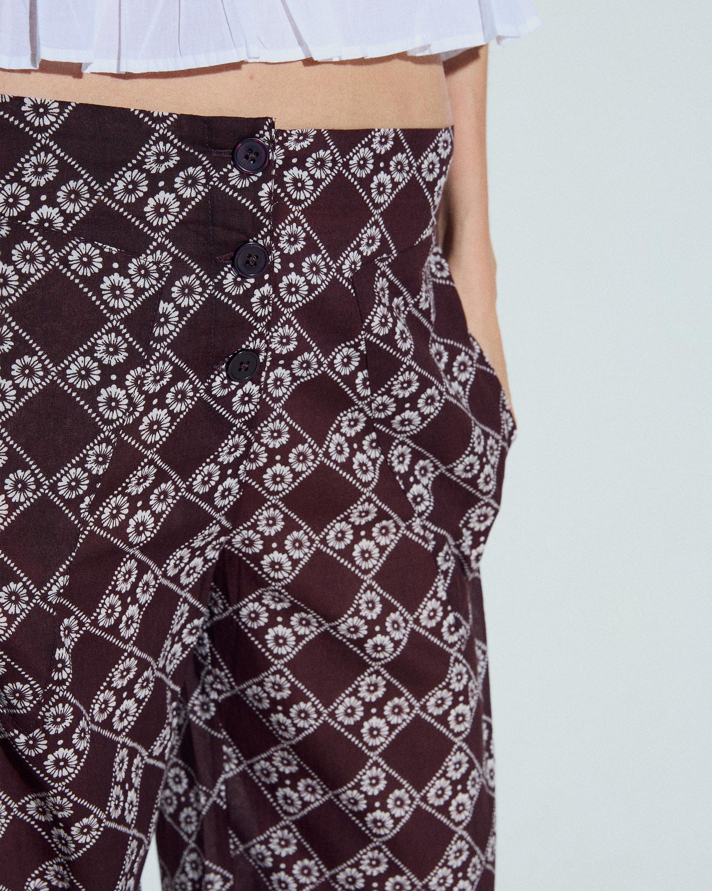 Calça fluída com estampado floral e três botões em castanho.