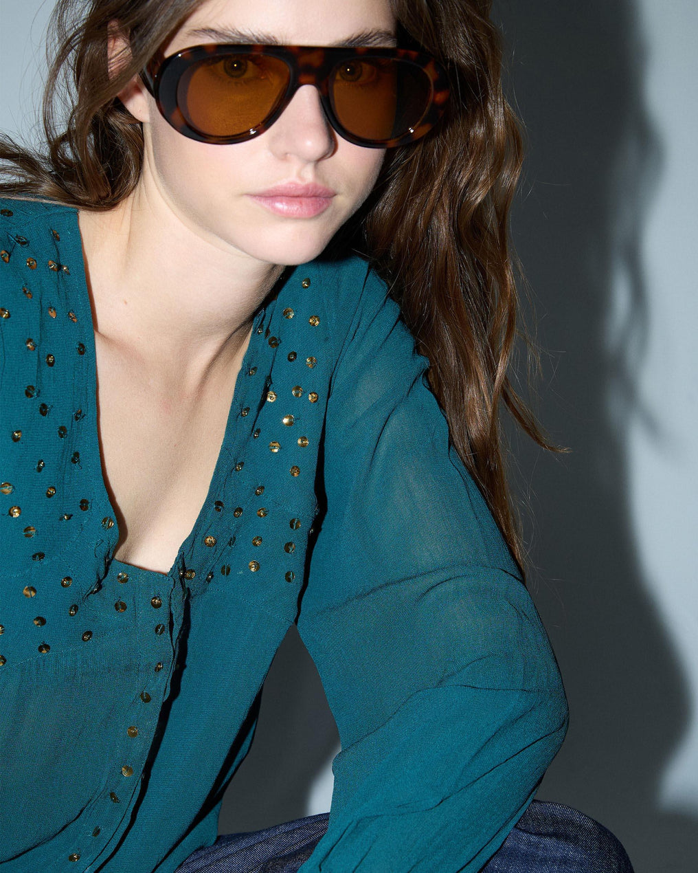 Blusa de lantejoulas, detalhe no decote em tom petróleo.