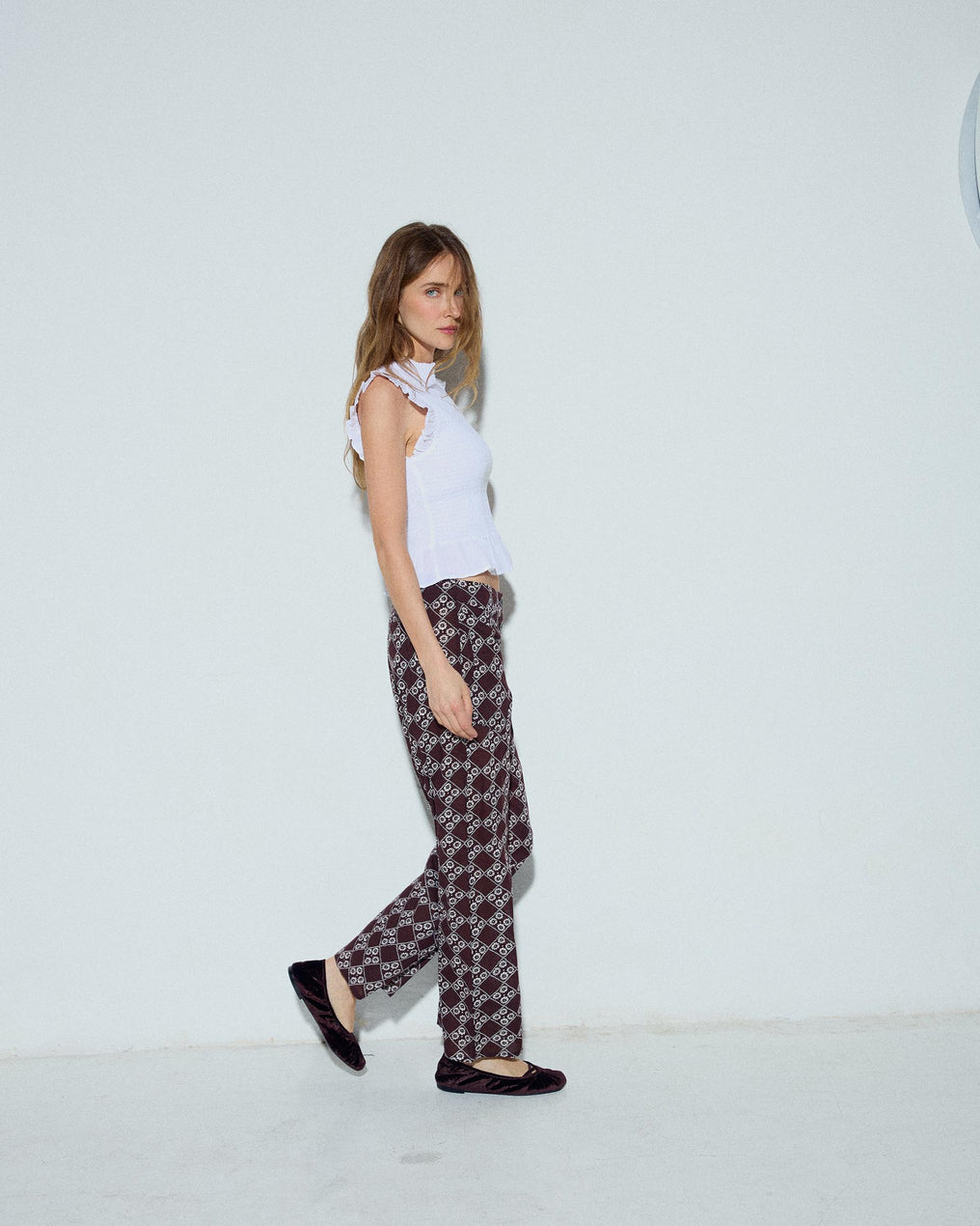 Calça fluída com estampado floral e três botões em castanho.