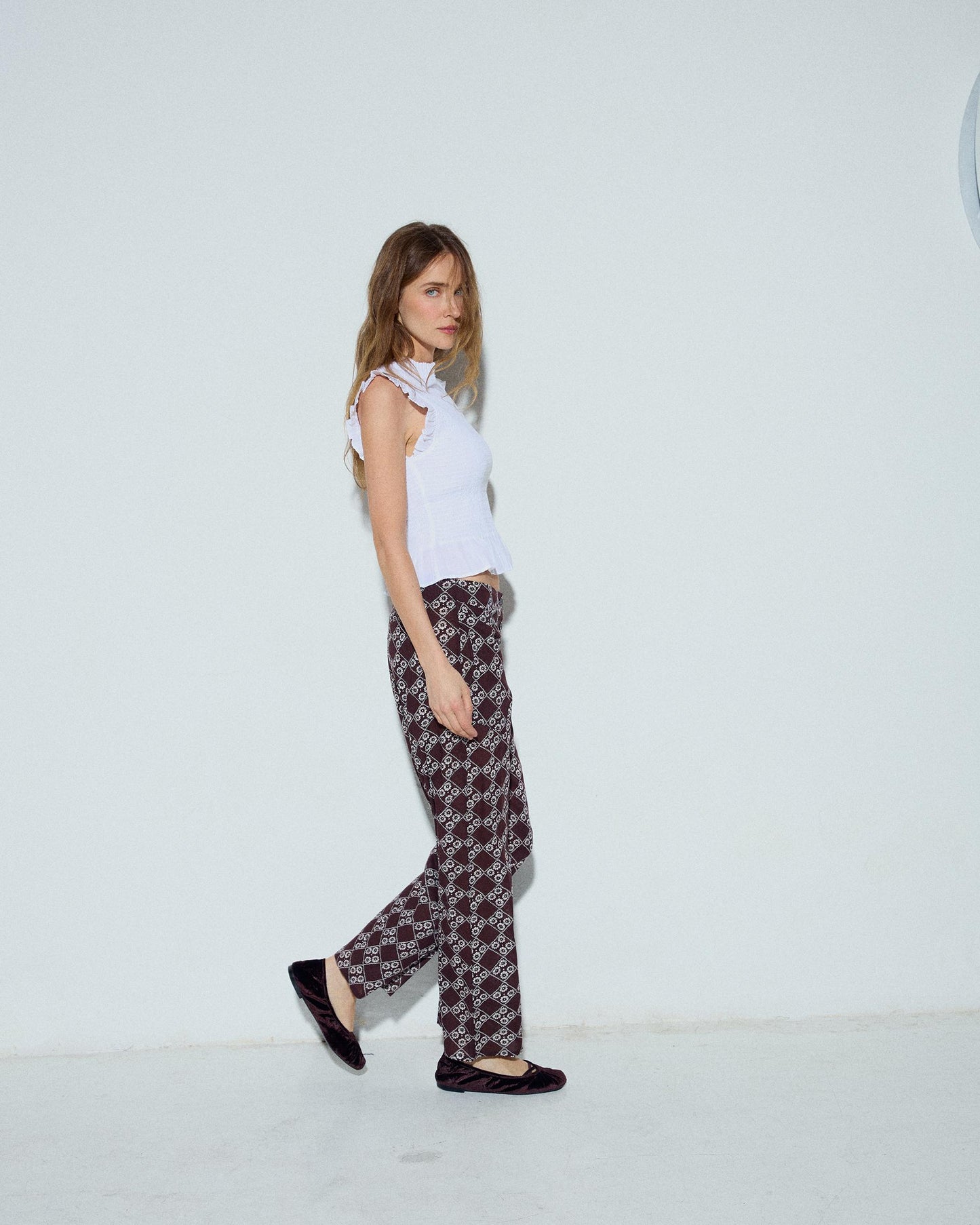 Calça fluída com estampado floral e três botões em castanho.