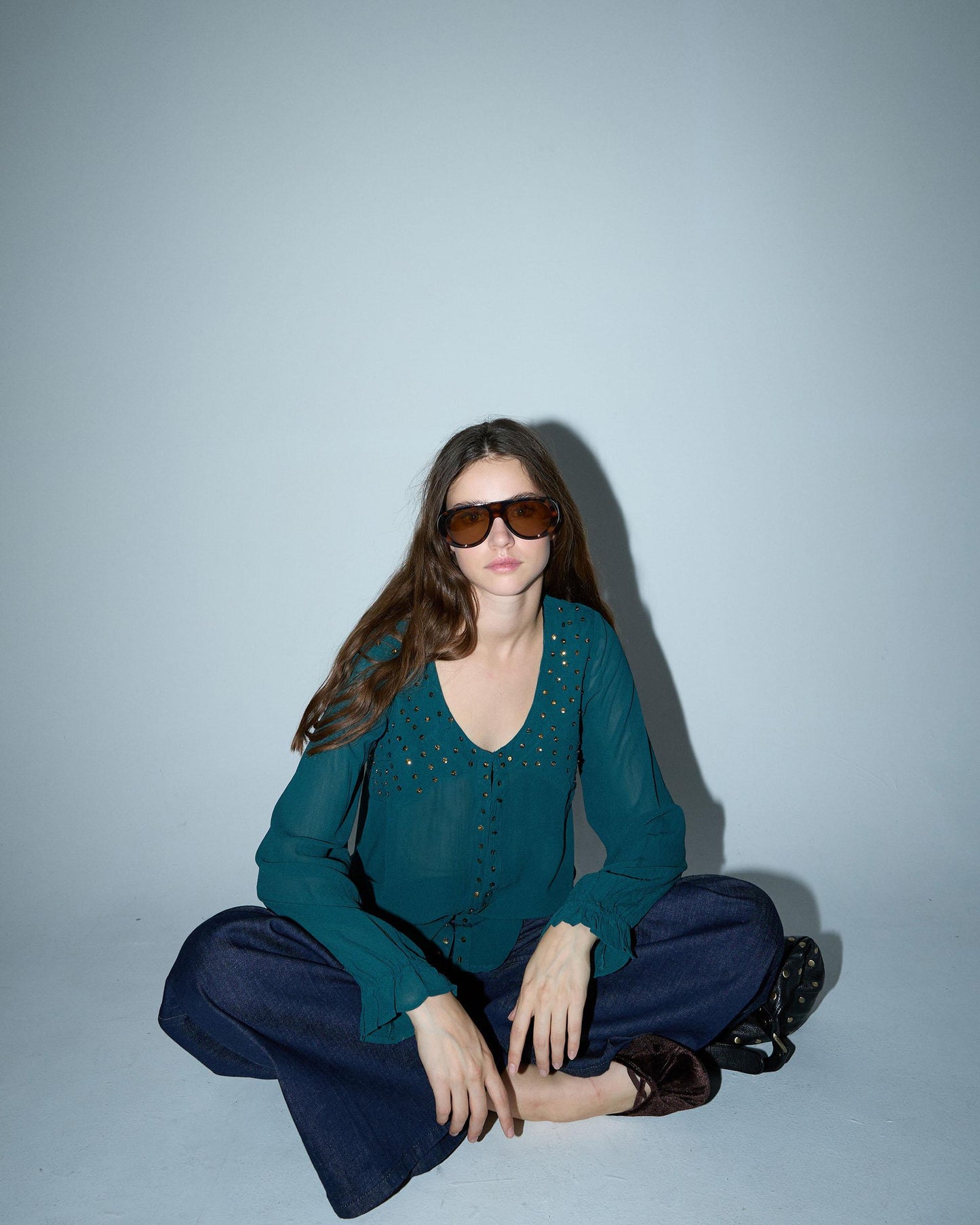 Blusa de lantejoulas, detalhe no decote em tom petróleo.