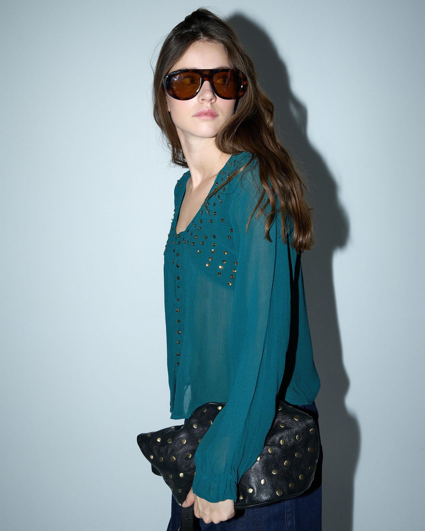 Blusa de lantejoulas, detalhe no decote em tom petróleo.