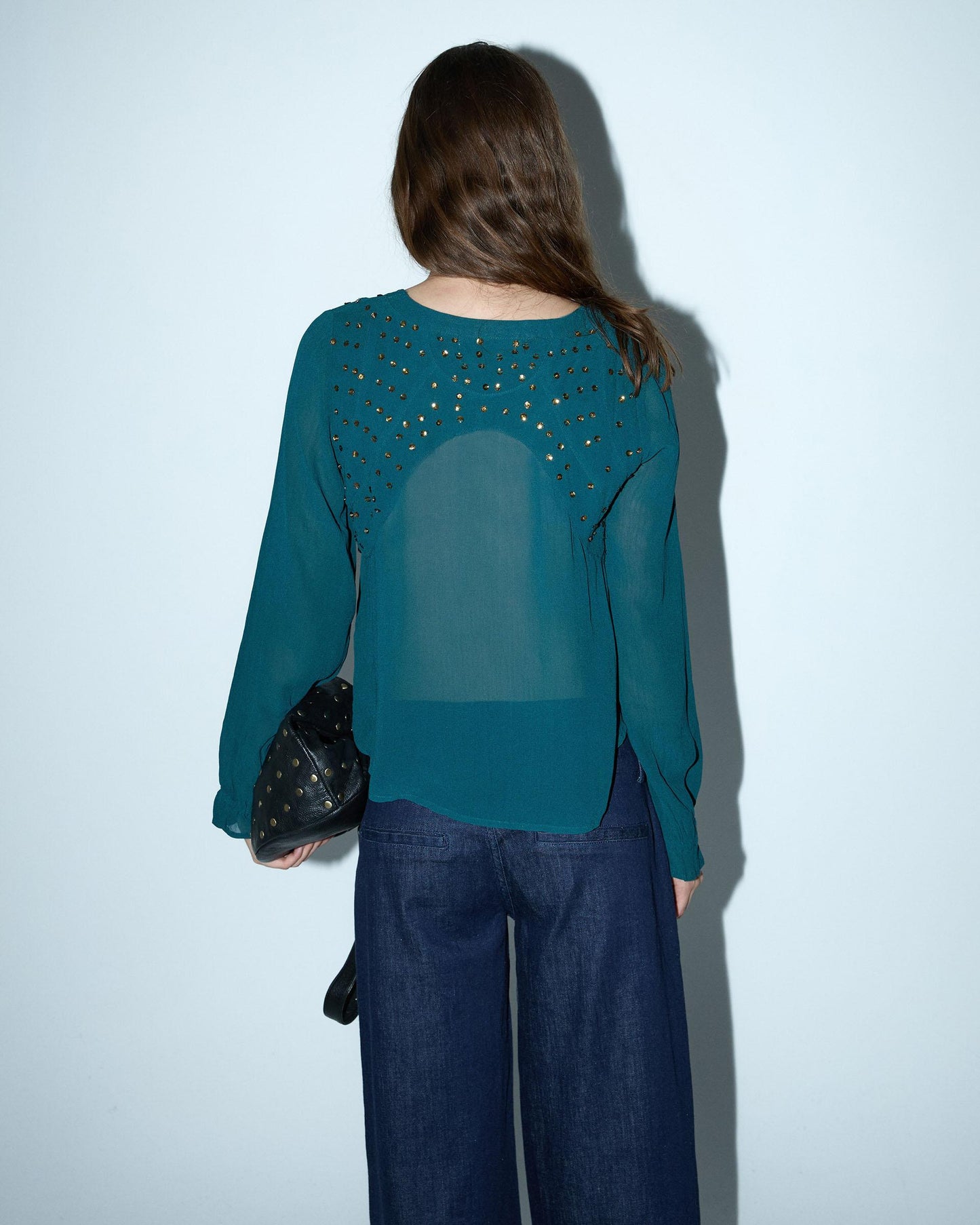 Blusa de lantejoulas, detalhe no decote em tom petróleo.